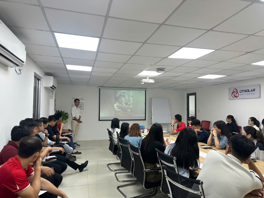 Ảnh chụp toàn cảnh phòng học, nhân viên chăm chú theo dõi màn hình máy chiếu video thực tế 

